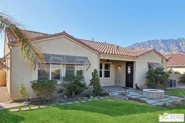 view of front of house featuring a mountain view, a fire pit, a patio area, and a front lawn