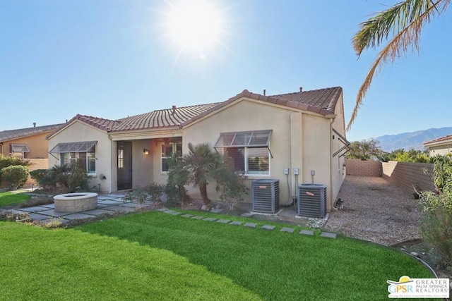 rear view of house featuring a lawn, cooling unit, and a fire pit