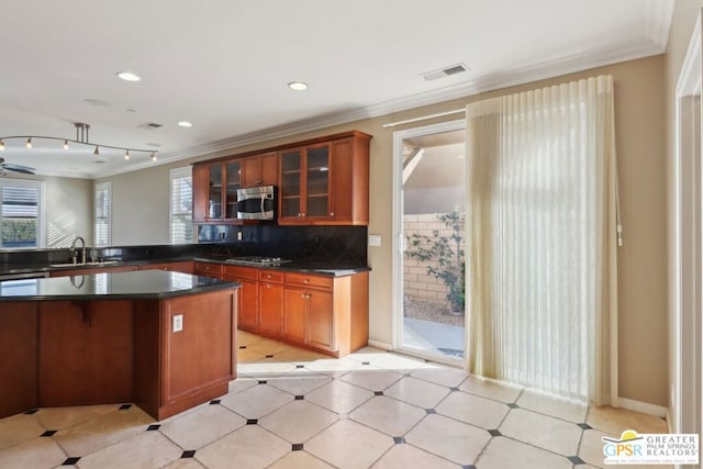 kitchen featuring crown molding, sink, a kitchen island, and backsplash