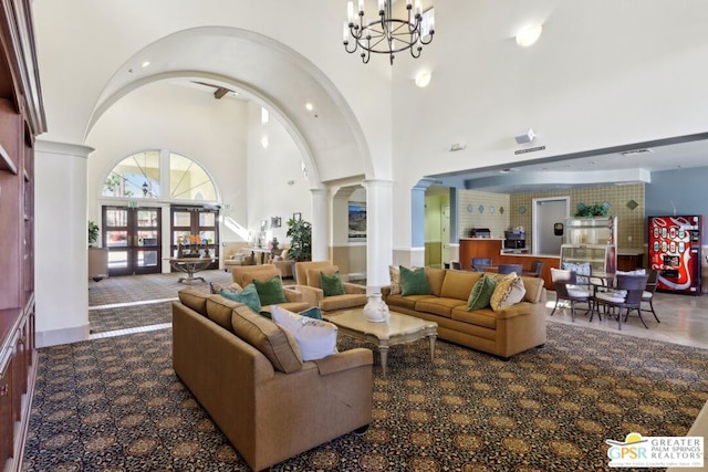 living room featuring an inviting chandelier, high vaulted ceiling, and decorative columns