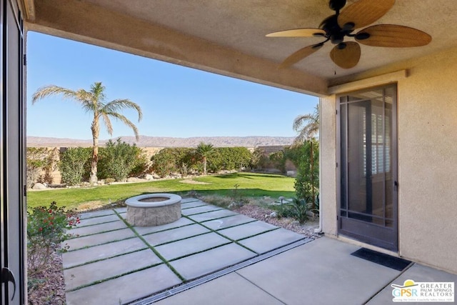 view of patio with ceiling fan, an outdoor fire pit, and a mountain view