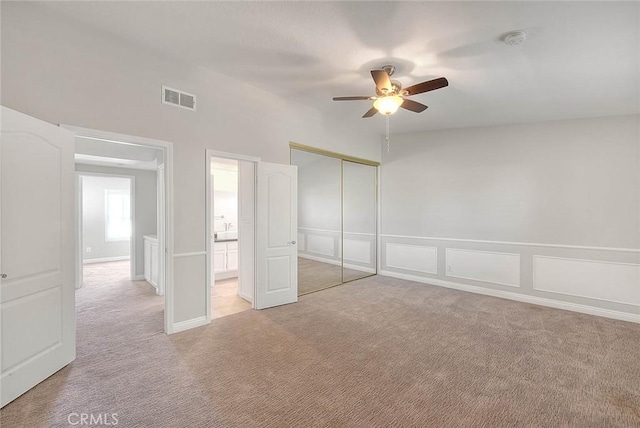 unfurnished bedroom with ceiling fan, light carpet, and a closet