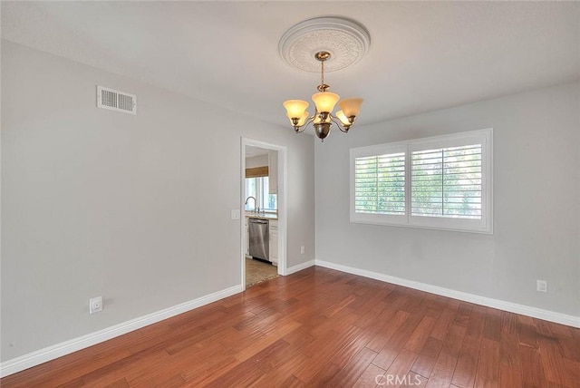 empty room with a chandelier, wood-type flooring, and sink