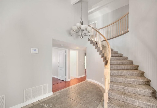 stairway featuring a towering ceiling and a chandelier