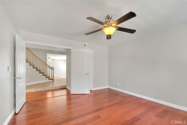 empty room with hardwood / wood-style floors, ceiling fan, and a textured ceiling