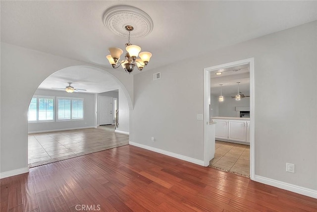 spare room featuring ceiling fan with notable chandelier and light hardwood / wood-style floors