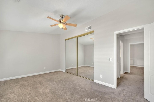 unfurnished bedroom with a closet, light colored carpet, and ceiling fan