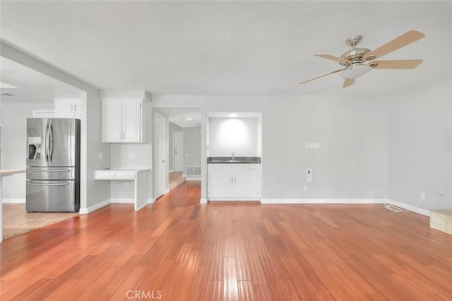 unfurnished living room with light hardwood / wood-style floors, ceiling fan, and sink