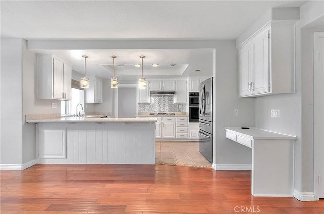 kitchen with white cabinetry, sink, kitchen peninsula, light hardwood / wood-style floors, and appliances with stainless steel finishes