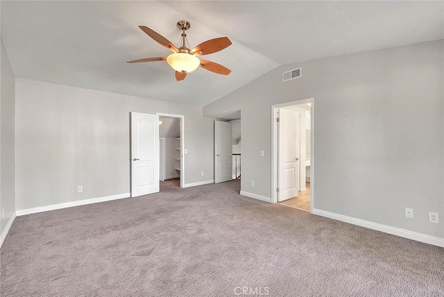 unfurnished bedroom featuring connected bathroom, a spacious closet, ceiling fan, vaulted ceiling, and carpet