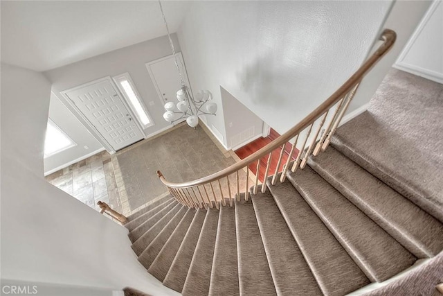 staircase featuring hardwood / wood-style floors and a notable chandelier