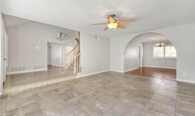 empty room with ceiling fan with notable chandelier and wood-type flooring