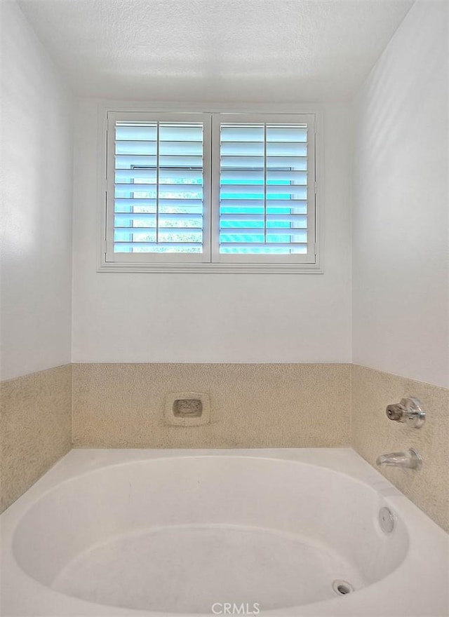 bathroom featuring a textured ceiling and a bathtub