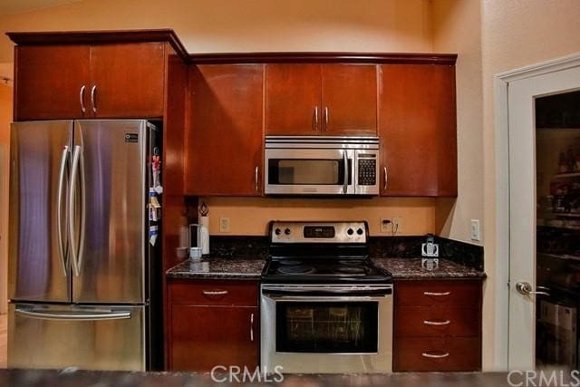 kitchen with stainless steel appliances and dark stone counters