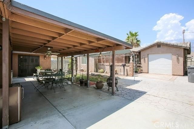 view of patio / terrace with a garage, ceiling fan, and an outbuilding