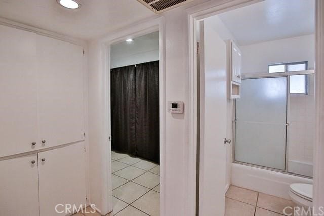 bathroom with enclosed tub / shower combo, toilet, and tile patterned floors