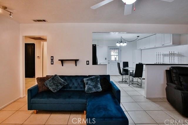 living room with ceiling fan with notable chandelier and light tile patterned floors