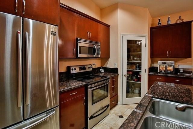 kitchen with dark stone countertops, appliances with stainless steel finishes, and sink