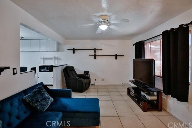 living room with ceiling fan, light tile patterned floors, and a textured ceiling