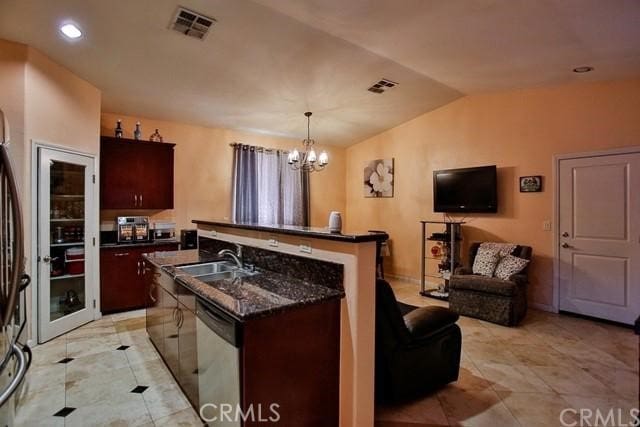 kitchen with an island with sink, hanging light fixtures, sink, dishwasher, and vaulted ceiling