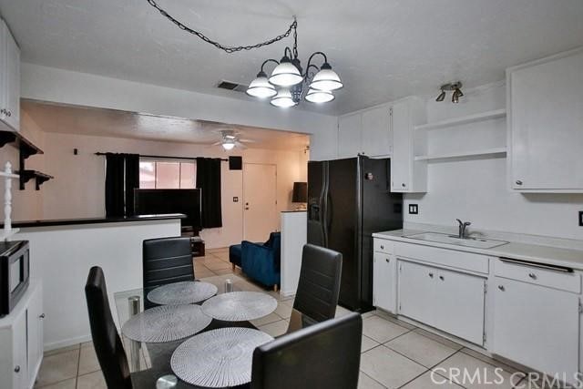 dining area featuring ceiling fan with notable chandelier, light tile patterned flooring, and sink