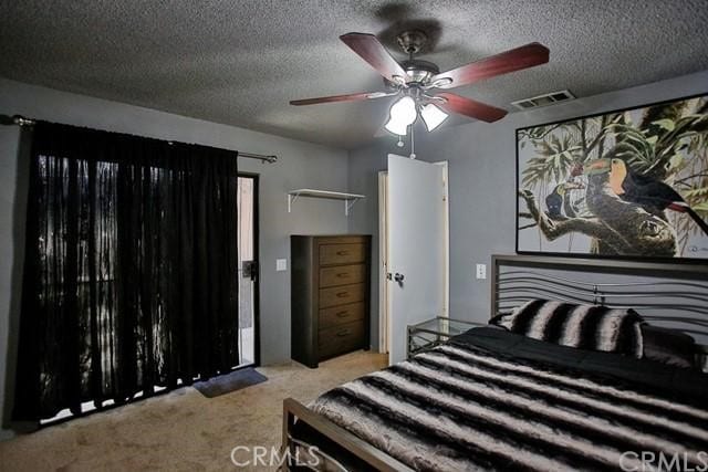 carpeted bedroom with ceiling fan and a textured ceiling