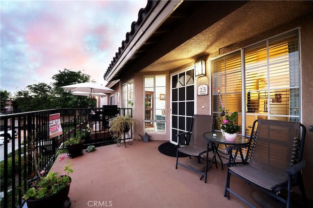 patio terrace at dusk featuring a balcony