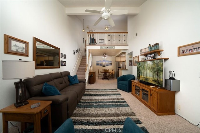 living room featuring ceiling fan, beamed ceiling, a towering ceiling, and light colored carpet