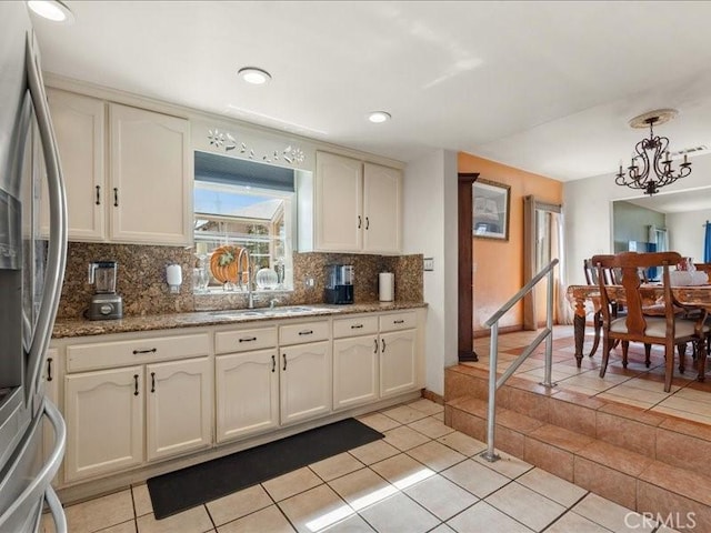 kitchen featuring decorative backsplash, stainless steel fridge with ice dispenser, light tile patterned floors, and dark stone counters