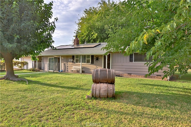 rear view of house featuring solar panels and a yard