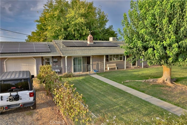 single story home featuring covered porch, a chimney, solar panels, and an attached garage