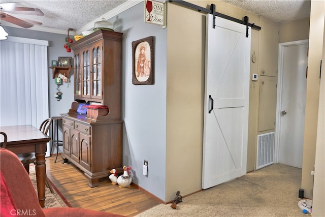 kitchen with a textured ceiling, a barn door, light wood-type flooring, and ceiling fan