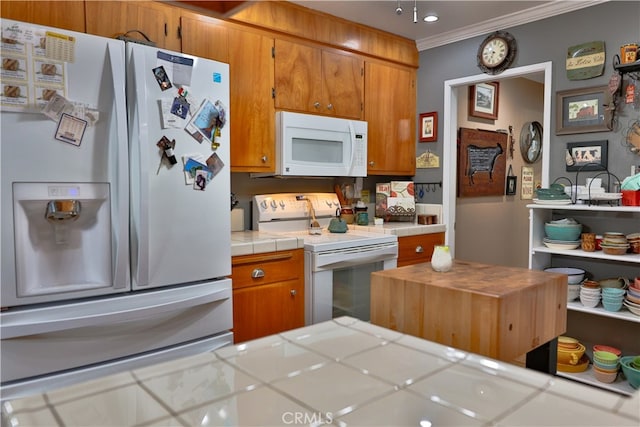 kitchen with ornamental molding, tile counters, and white appliances