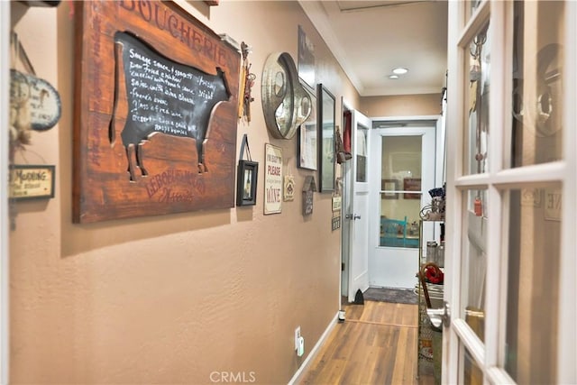corridor with crown molding, wood finished floors, and baseboards