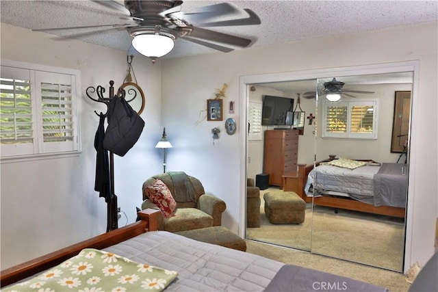 bedroom with a textured ceiling, ceiling fan, carpet flooring, and a closet