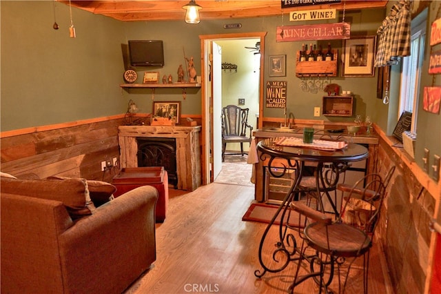 dining room with beamed ceiling, wooden walls, indoor bar, and light hardwood / wood-style floors