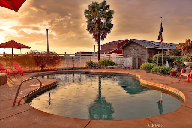 pool at dusk featuring a patio