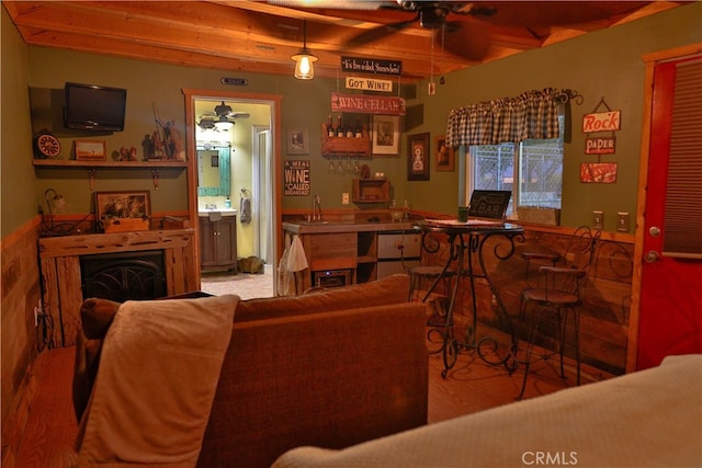 living room with beam ceiling, indoor wet bar, light hardwood / wood-style floors, and ceiling fan