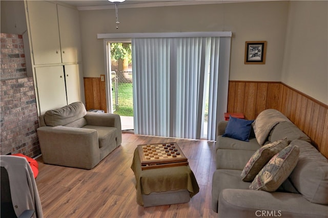 living room with crown molding, hardwood / wood-style flooring, and brick wall