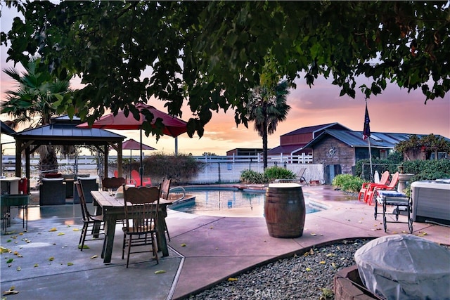 patio terrace at dusk featuring a fenced in pool