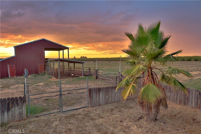 yard at dusk featuring a rural view and an outdoor structure