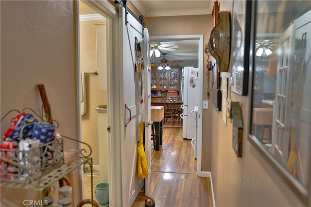 hall with crown molding, wood-type flooring, and a barn door