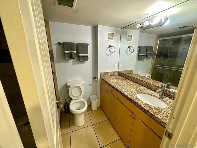 bathroom featuring vanity, toilet, tile patterned floors, and a shower with shower door