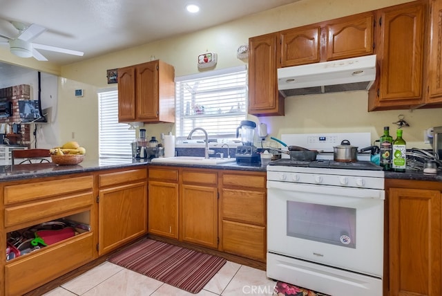 kitchen featuring ceiling fan, light tile patterned floors, sink, and gas range gas stove