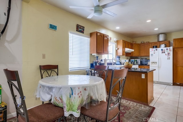 kitchen with a center island, white refrigerator with ice dispenser, sink, light tile patterned floors, and ceiling fan