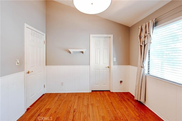 unfurnished room featuring lofted ceiling, light hardwood / wood-style flooring, and a wealth of natural light