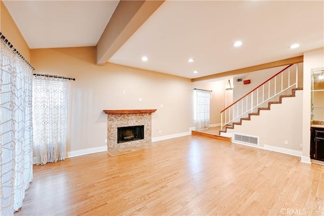 unfurnished living room featuring beamed ceiling and light hardwood / wood-style floors