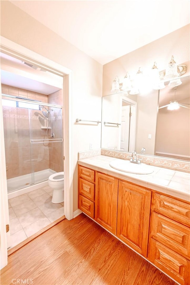 bathroom featuring wood-type flooring, toilet, an enclosed shower, and vanity