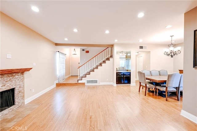 living room with a fireplace, a chandelier, and light wood-type flooring