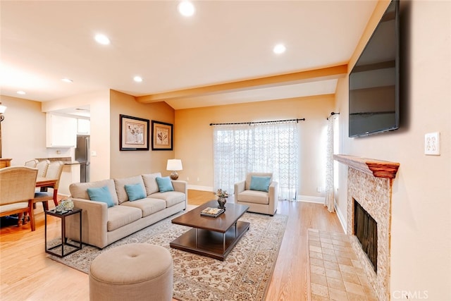 living room with vaulted ceiling with beams, a fireplace, and light hardwood / wood-style floors